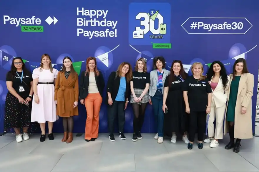 Група хора пред екран с надпис „Happy Birthday Paysafe“ и числото 30.