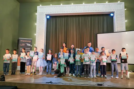 Две момчета вдигат зелено-бели сертификати пред тъмна завеса