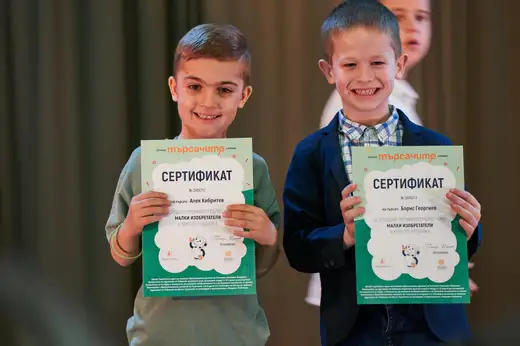 Две момчета показват сертификатите си, до тях трето дете.